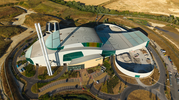 Aerial view of the Energy Recovery Facility with its curved roof and tall chimneys surrounded by industrial infrastructure and parking areas Bicester England United Kingdom.