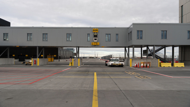 View of an airport tarmac and apron area featuring a jet bridge marked 80R in Iceland.