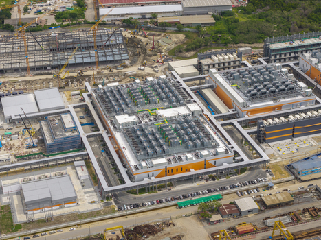 Aerial view of a large hyperscale data center facility featuring extensive rooftop cooling units industrial architecture and surrounding construction sites in Asia. Aerial view of a large hyperscale data center facility featuring extensive rooftop cooling units industrial architecture and surrounding construction sites in Asia.