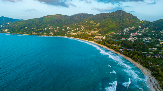 Aerial view of Anse Soleil Beachcomber Hotel nestled along the lush coastline of Mahe with turquoise waters sandy beaches and green hills. Mahe Baie Lazare Seychelles.