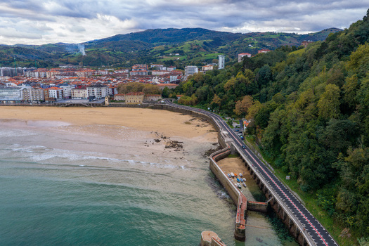 Aerial view of Puerto de Zarautz featuring the sandy beach coastal road and the town architecture under a cloudy sky in Zarautz Basque Country Spain.