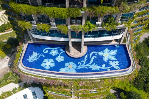 Aerial view of Forest City high rise building featuring a swimming pool with floral mosaic patterns surrounded by lush vertical gardens in Gelang Patah Johor Darul Ta zim Malaysia. Aerial view of Forest City high rise building featuring a swimming pool with floral mosaic patterns surrounded by lush vertical gardens in Gelang Patah Johor Darul Ta zim Malaysia.