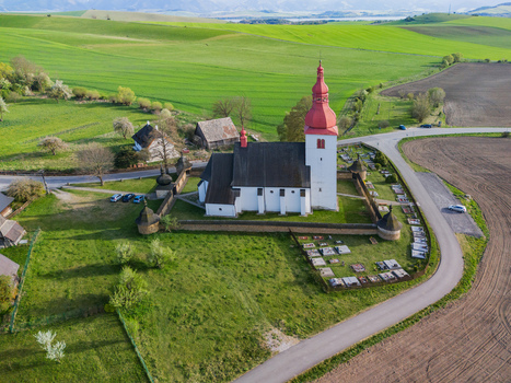 Aerial view of the historic Church of Saint Ladislaus with its distinctive red steeple and stone fortification wall surrounded by green fields in Liptovske Matiasovce Zilina Region Slovakia.