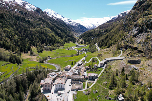 Aerial view of the alpine village of Valgrisenche with its traditional stone buildings and green meadows surrounded by snow capped mountains Valgrisenche Aosta Valley Italy.