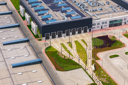 Aerial view of the modern Zajezdnia Annopol 01 tram depot with tracks leading into the facility solar panels on the roof and landscaped green areas in Warsaw Masovian Voivodeship Poland. Aerial view of the modern Zajezdnia Annopol 01 tram depot with tracks leading into the facility solar panels on the roof and landscaped green areas in Warsaw Masovian Voivodeship Poland.
