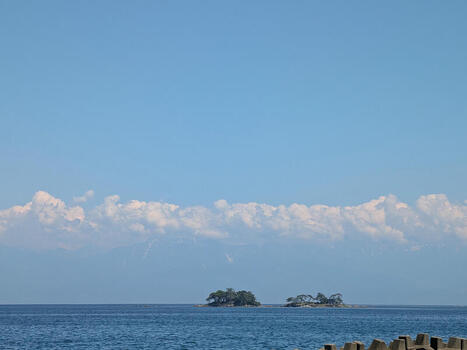View of the calm sea with small islands and distant mountains under a clear blue sky in Himi Toyama Japan.