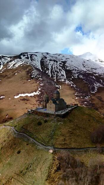 Aerial view of Gergeti Trinity Church and snowy mountains Georgia.