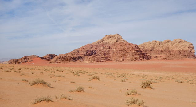 View of the vast red sand dunes and dramatic sandstone mountains of the Wadi Rum Desert under a clear blue sky in Wadi Rum Village Aqaba Governorate Jordan. View of the vast red sand dunes and dramatic sandstone mountains of the Wadi Rum Desert under a clear blue sky in Wadi Rum Village Aqaba Governorate Jordan.