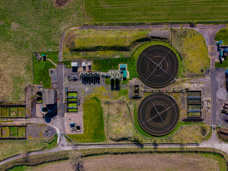 Aerial view of the Gnosall Heath sewage treatment plant featuring circular sedimentation tanks green aeration basins and surrounding rural fields in Gnosall England United Kingdom. Aerial view of the Gnosall Heath sewage treatment plant featuring circular sedimentation tanks green aeration basins and surrounding rural fields in Gnosall England United Kingdom.