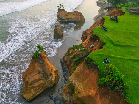 Aerial view of the dramatic coastal cliffs and sea stacks at sunset with lush green grass on the cliff edge and waves crashing against the shore in Bali Bali Indonesia. Aerial view of the dramatic coastal cliffs and sea stacks at sunset with lush green grass on the cliff edge and waves crashing against the shore in Bali Bali Indonesia.