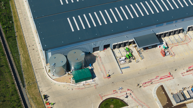 Aerial view of Symmetry Park showing a large warehouse with loading docks industrial storage tanks and a paved logistics yard in Kettering England United Kingdom. Aerial view of Symmetry Park showing a large warehouse with loading docks industrial storage tanks and a paved logistics yard in Kettering England United Kingdom.