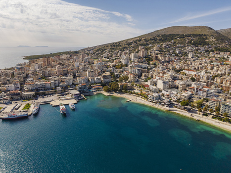 Aerial view of the coastal city of Saranda with its harbor boats and urban buildings nestled against the hills along the Ionian Sea in Saranda Vlore County Albania. Aerial view of the coastal city of Saranda with its harbor boats and urban buildings nestled against the hills along the Ionian Sea in Saranda Vlore County Albania.