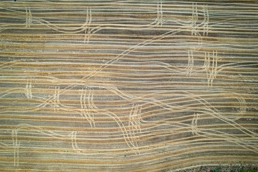 Aerial view of a harvested agricultural field featuring intricate tractor tire tracks across golden straw stubble in Carignano Piemonte Italy. Aerial view of a harvested agricultural field featuring intricate tractor tire tracks across golden straw stubble in Carignano Piemonte Italy.