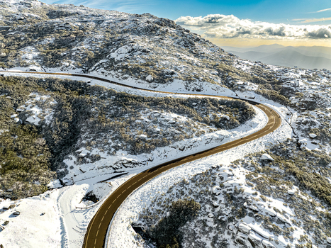 Aerial view of a winding road cutting through the snow dusted Serra da Estrela mountains under a bright sky São Romão Guarda District Portugal. Aerial view of a winding road cutting through the snow dusted Serra da Estrela mountains under a bright sky São Romão Guarda District Portugal.