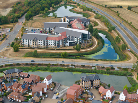 Aerial view of Wixams Retirement Village featuring modern residential buildings with red tiled roofs surrounded by landscaped ponds and green spaces in Bedford England United Kingdom.