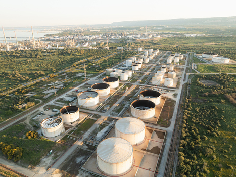 Aerial view of an industrial oil refinery with large storage tanks surrounded by green fields and coastal landscape in Augusta Sicily Italy. Aerial view of an industrial oil refinery with large storage tanks surrounded by green fields and coastal landscape in Augusta Sicily Italy.