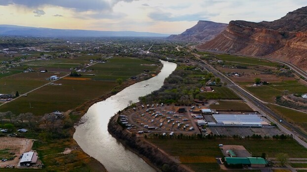 Aerial view of the Colorado River snaking through the lush green valleys contrasting with the towering red rock formations Palisade Colorado USA. Aerial view of the Colorado River snaking through the lush green valleys contrasting with the towering red rock formations Palisade Colorado USA.