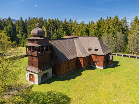 Aerial view of the Wooden Articular Church of Svaty Kriz surrounded by a green meadow and dense evergreen forest Svaty Kriz Zilinsky kraj Slovakia.
