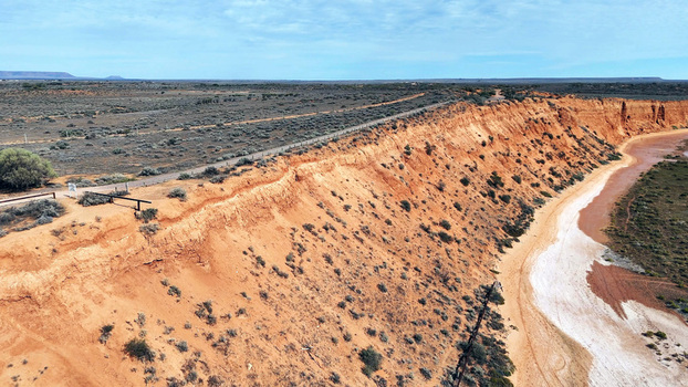 Aerial view of the Matthew Flinders Red Cliff Lookout featuring dramatic red earth cliffs desert vegetation and a road along the ridge in Port Augusta West South Australia Australia. Aerial view of the Matthew Flinders Red Cliff Lookout featuring dramatic red earth cliffs desert vegetation and a road along the ridge in Port Augusta West South Australia Australia.