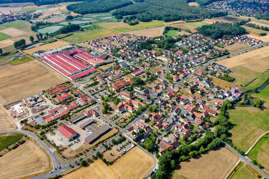 Aerial view of residential neighborhoods a large industrial facility with red roofs and lush green fields in Gremsdorf Bavaria Germany. Aerial view of residential neighborhoods a large industrial facility with red roofs and lush green fields in Gremsdorf Bavaria Germany.