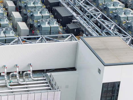 Aerial view of a data center rooftop featuring industrial cooling fans metal piping and technical infrastructure in the United Kingdom. Aerial view of a data center rooftop featuring industrial cooling fans metal piping and technical infrastructure in the United Kingdom.