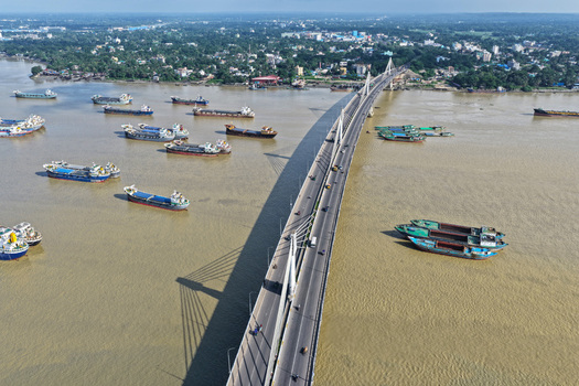 Aerial view of the Shah Amanat Bridge spanning the Karnaphuli River with numerous cargo ships navigating the waterway in Chattogram Chittagong Division Bangladesh.