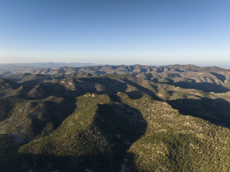 Aerial view of the rugged landscape of the Sierra de San Miguelito Norte featuring rolling hills covered in dense vegetation under a clear blue sky in San Luis Potosi San Luis Potosi Mexico. Aerial view of the rugged landscape of the Sierra de San Miguelito Norte featuring rolling hills covered in dense vegetation under a clear blue sky in San Luis Potosi San Luis Potosi Mexico.