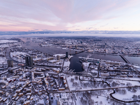 Aerial view of the snow covered city of Riga with the Daugava river bridges and urban architecture under a soft winter sky in Riga Latvia.