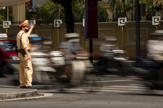 Hanoi Ha Noi Vietnam 11 November 2025 View of a traffic police officer in uniform directing the flow of motorbikes on a busy street in Hanoi.