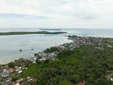 Aerial view of a vibrant coastal town where emerald forests meet the turquoise sea contrasting with the terracotta rooftops Karimunjawa Central Java Indonesia. Aerial view of a vibrant coastal town where emerald forests meet the turquoise sea contrasting with the terracotta rooftops Karimunjawa Central Java Indonesia.