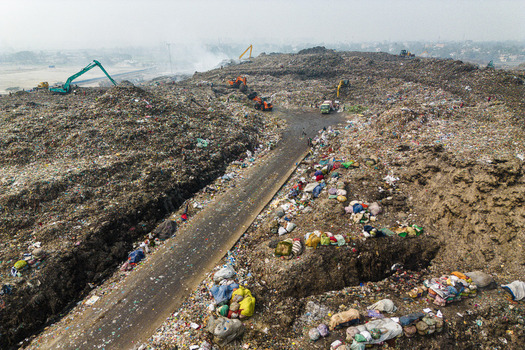 Aminbazar Bangladesh 26 January 2025 Aerial view of the massive Aminbazar landfill with excavators and trucks moving waste along a dirt road under a hazy sky. Aminbazar Bangladesh 26 January 2025 Aerial view of the massive Aminbazar landfill with excavators and trucks moving waste along a dirt road under a hazy sky.
