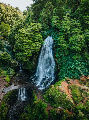 Aerial view of a cascading waterfall plunges into a serene pool embraced by vibrant green foliage Achada Açores Portugal. Aerial view of a cascading waterfall plunges into a serene pool embraced by vibrant green foliage Achada Açores Portugal.