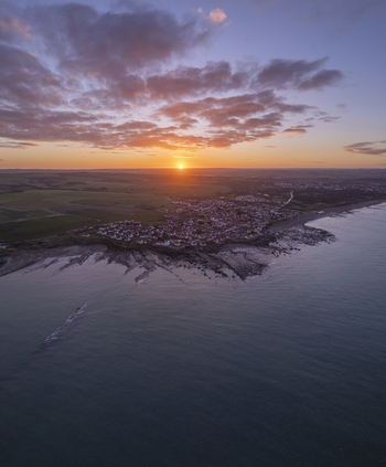 Aerial view of the coastal village of Audresselles at sunset with rocky shoreline and calm sea in Audresselles Hauts de France France.