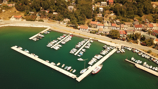 Aerial view of the marina with small boats moored at concrete piers surrounded by coastal houses and trees along the Adriatic Sea in Bakarac Primorje Gorski Kotar Croatia. Aerial view of the marina with small boats moored at concrete piers surrounded by coastal houses and trees along the Adriatic Sea in Bakarac Primorje Gorski Kotar Croatia.