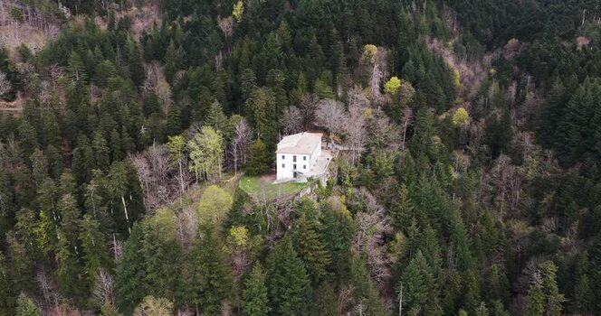 Aerial view of a secluded white building in a dense forest Italy. Aerial view of a secluded white building in a dense forest Italy.
