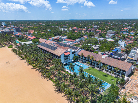 Aerial view of Negombo Beach resort featuring swimming pools lush palm trees and a hotel building with solar panels along the coastline in Negombo Western Province Sri Lanka. Aerial view of Negombo Beach resort featuring swimming pools lush palm trees and a hotel building with solar panels along the coastline in Negombo Western Province Sri Lanka.