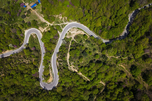 Aerial view of the winding road through the lush green forests of the Muzine Pass in Muzina Qarku i Vlores Albania. Aerial view of the winding road through the lush green forests of the Muzine Pass in Muzina Qarku i Vlores Albania.