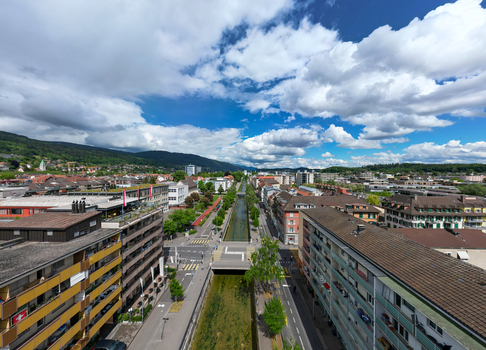 Aerial view of the Schuss canal flowing through the urban landscape with residential buildings and green hills under a cloudy sky in Biel Bienne Canton of Bern Switzerland. Aerial view of the Schuss canal flowing through the urban landscape with residential buildings and green hills under a cloudy sky in Biel Bienne Canton of Bern Switzerland.