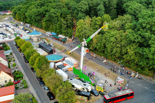Forchheim Germany 25 July 2025 Aerial view of the Annafest fairground featuring colorful amusement rides crowds of people and parked vehicles next to a lush green forest. Forchheim Germany 25 July 2025 Aerial view of the Annafest fairground featuring colorful amusement rides crowds of people and parked vehicles next to a lush green forest.