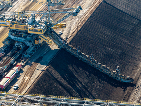 Aerial view of the Tagebau Welzow Sud brown coal open pit mine featuring a massive bucket wheel excavator extracting coal from dark earth layers in Spremberg Brandenburg Germany. Aerial view of the Tagebau Welzow Sud brown coal open pit mine featuring a massive bucket wheel excavator extracting coal from dark earth layers in Spremberg Brandenburg Germany.