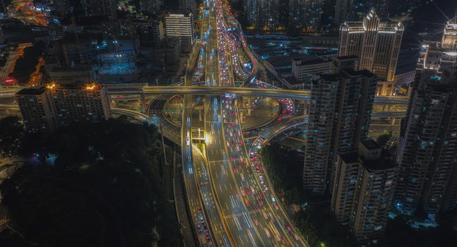 Aerial view of the Tianmu Road Interchange at night with heavy traffic flow and light trails surrounded by illuminated skyscrapers in Shanghai Shanghai China. Aerial view of the Tianmu Road Interchange at night with heavy traffic flow and light trails surrounded by illuminated skyscrapers in Shanghai Shanghai China.