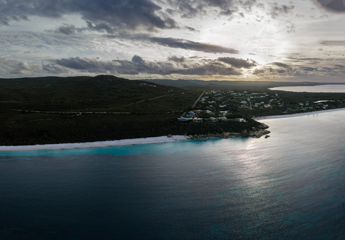 Aerial view of Frenchman Bay featuring turquoise waters white sand beach coastal vegetation and residential houses under a cloudy sunset sky in Albany Western Australia Australia. Aerial view of Frenchman Bay featuring turquoise waters white sand beach coastal vegetation and residential houses under a cloudy sunset sky in Albany Western Australia Australia.