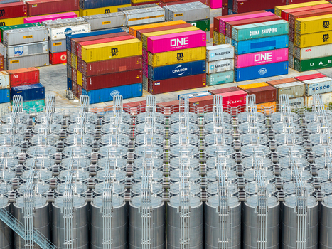 Poland 25 July 2026 Aerial view of a shipping containers hub with colorful stacked containers and rows of industrial storage tanks in the foreground.