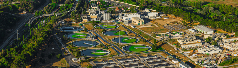 Aerial view of a water treatment plant with circular sedimentation tanks industrial buildings and surrounding greenery in Rome Lazio Italy.