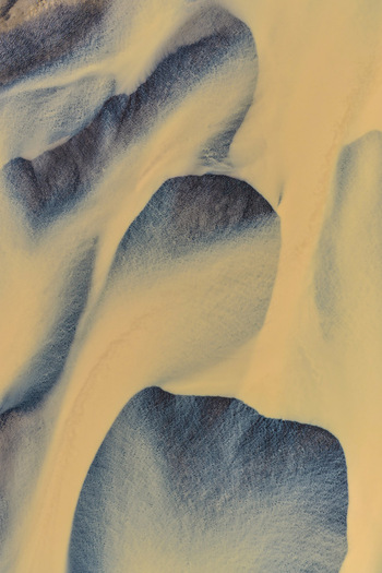 Aerial view of the intricate braided river patterns of Drangajokull featuring sediment rich glacial water flowing through dark volcanic sand in Isafjordur Isafjardarbaer Iceland. Aerial view of the intricate braided river patterns of Drangajokull featuring sediment rich glacial water flowing through dark volcanic sand in Isafjordur Isafjardarbaer Iceland.