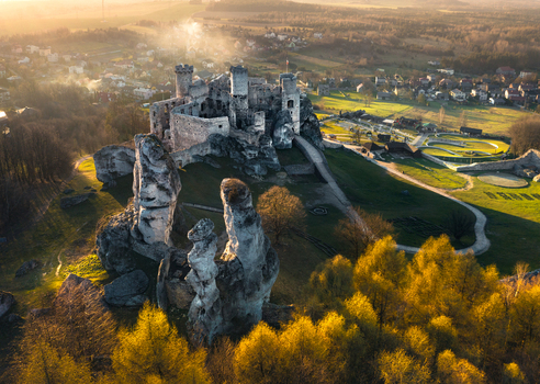 Aerial view of the medieval ruins of Ogrodzieniec Castle perched on limestone rocks during a golden sunset in Krakow County Lesser Poland Voivodeship Poland. Aerial view of the medieval ruins of Ogrodzieniec Castle perched on limestone rocks during a golden sunset in Krakow County Lesser Poland Voivodeship Poland.