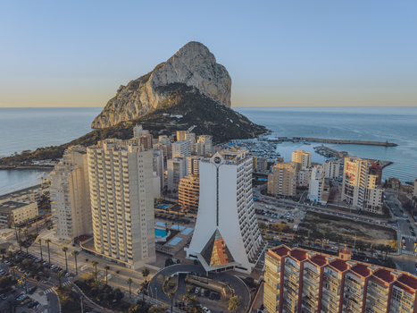 Aerial view of the Penon de Ifach limestone rock formation towering over the coastal town of Calp featuring modern high rise hotels and a marina in Calp Valencian Community Spain. Aerial view of the Penon de Ifach limestone rock formation towering over the coastal town of Calp featuring modern high rise hotels and a marina in Calp Valencian Community Spain.