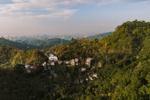 Cebu City Philippines 20 May 2026 Aerial view of Busay hillside with residential houses nestled among lush tropical greenery overlooking the distant Cebu City skyline.