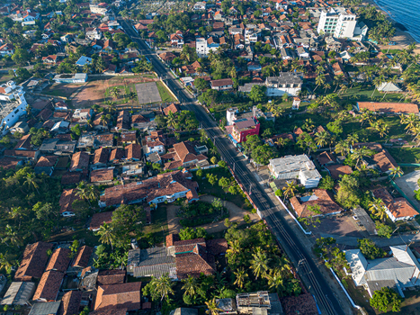 Aerial view of the coastal town with dense residential rooftops palm trees and roads leading towards the shoreline near Negombo Beach Negombo Western Province Sri Lanka. Aerial view of the coastal town with dense residential rooftops palm trees and roads leading towards the shoreline near Negombo Beach Negombo Western Province Sri Lanka.