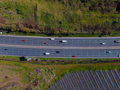 Aerial view of the M6 motorway with cars driving along the multi lane road surrounded by green fields and agricultural land in Penkridge England United Kingdom. Aerial view of the M6 motorway with cars driving along the multi lane road surrounded by green fields and agricultural land in Penkridge England United Kingdom.